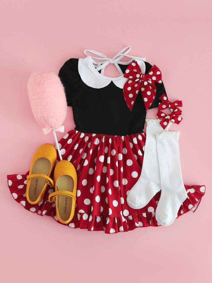 flat lay of styled Minnie inspired twirl dress with black bodice, red with white polka dot skirt and white peter pan collar paired with matching accessories and yellow mary janes