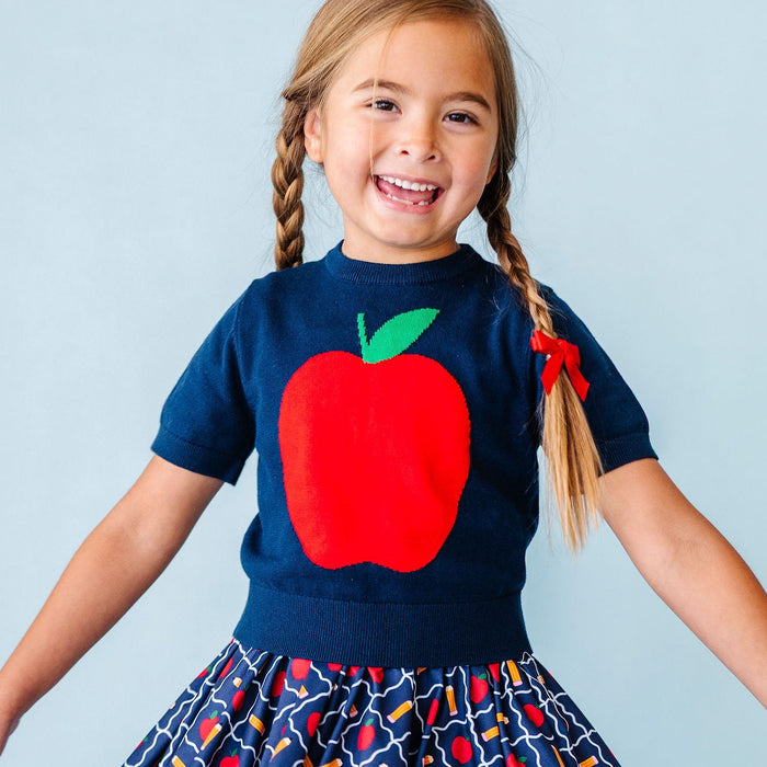 girl wearing school outfit with apples and pencils and big red apple top