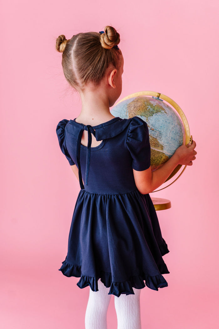 girl wearing navy cotton dress with collar and white cable knit tights