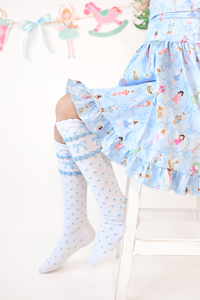 closeup of white scalloped knee socks with blue polka dots and bows paired with blue nutcracker print twirl dress for Christmas