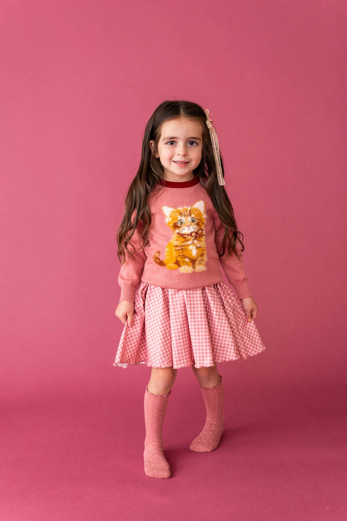 little girl in pink gingham twirl with pink cat design sweater layered on top and matching pink dot knee socks