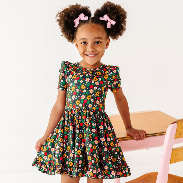 little girl wearing forest green floral print with apples and bright flowers for back to school