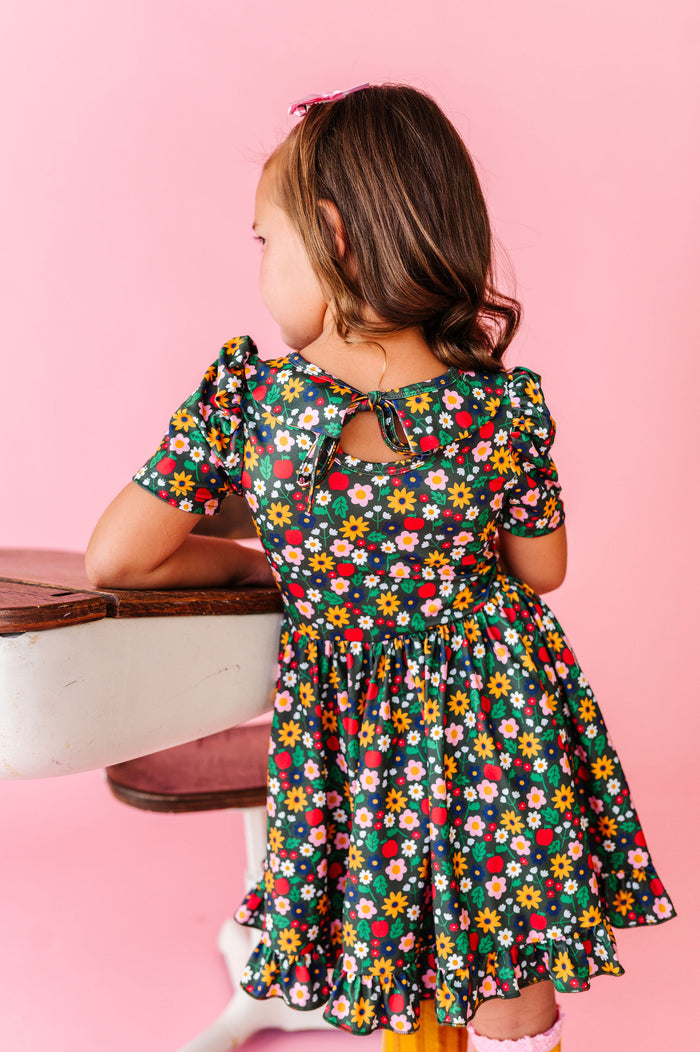 girl wearing back to school floral dress with flowers and apples and bow tie back