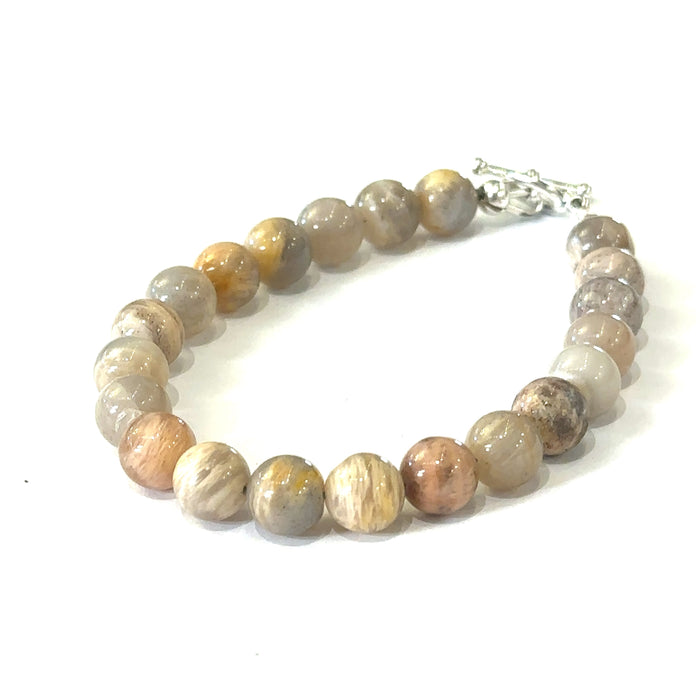 A greyish peach Moonstone gemstone beaded bracelet with a sterling silver toggle clasp on a white background, front, slight left angle overview.