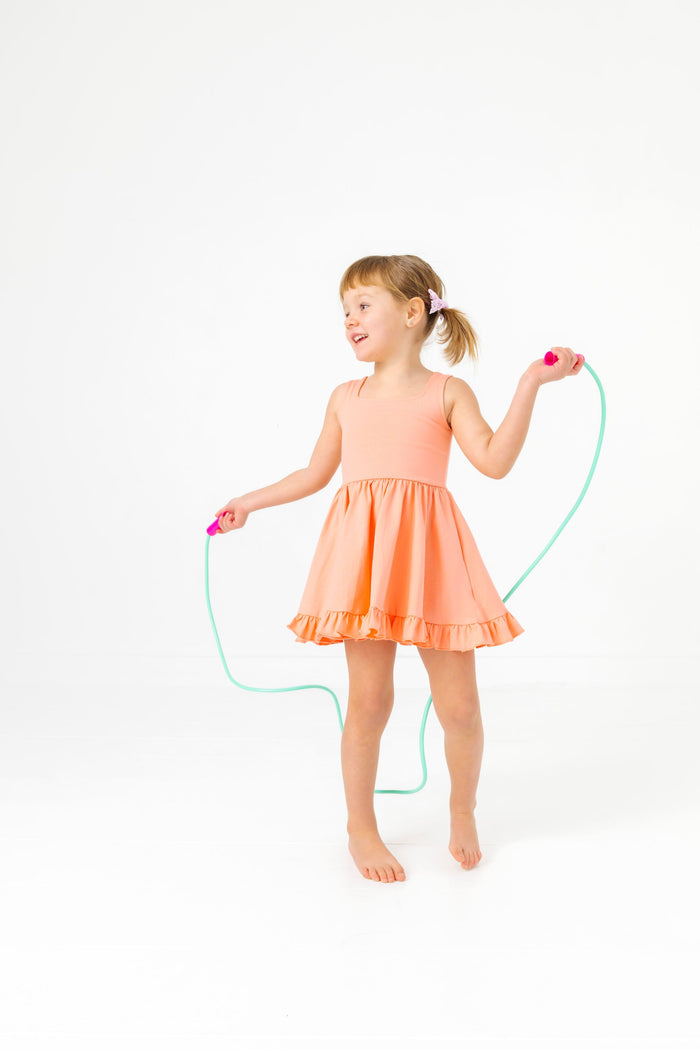 little girl jumping rope in peach sleeveless twirl dress and lavender lace pigtail bows