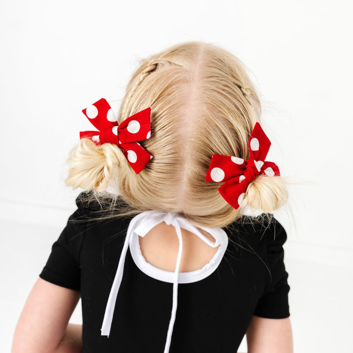 little girl in pigtails with red and white polka dot pigtail bows on clips to match Minnie inspired twirl dress