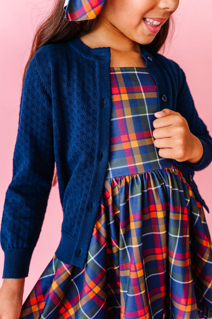 girl wearing navy pointelle knit cardigan over back to school plaid dress