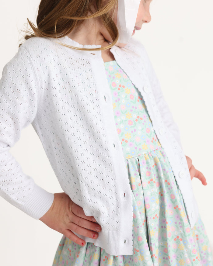 young girl in mint twirl dress with spring floral print paired with pointelle cotton knit button front sweater in white