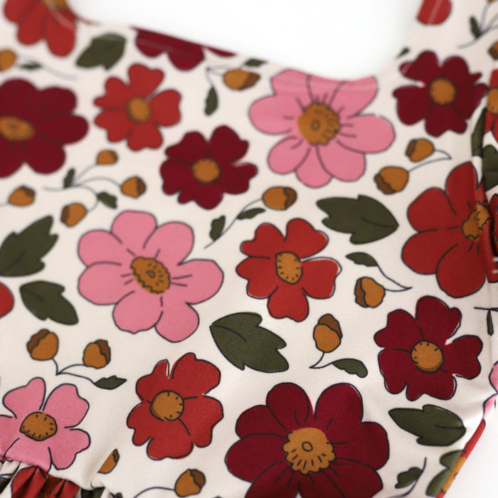 closeup of twirl dress floral print in shades of rust, burgundy and rose with olive and mustard accents on cream
