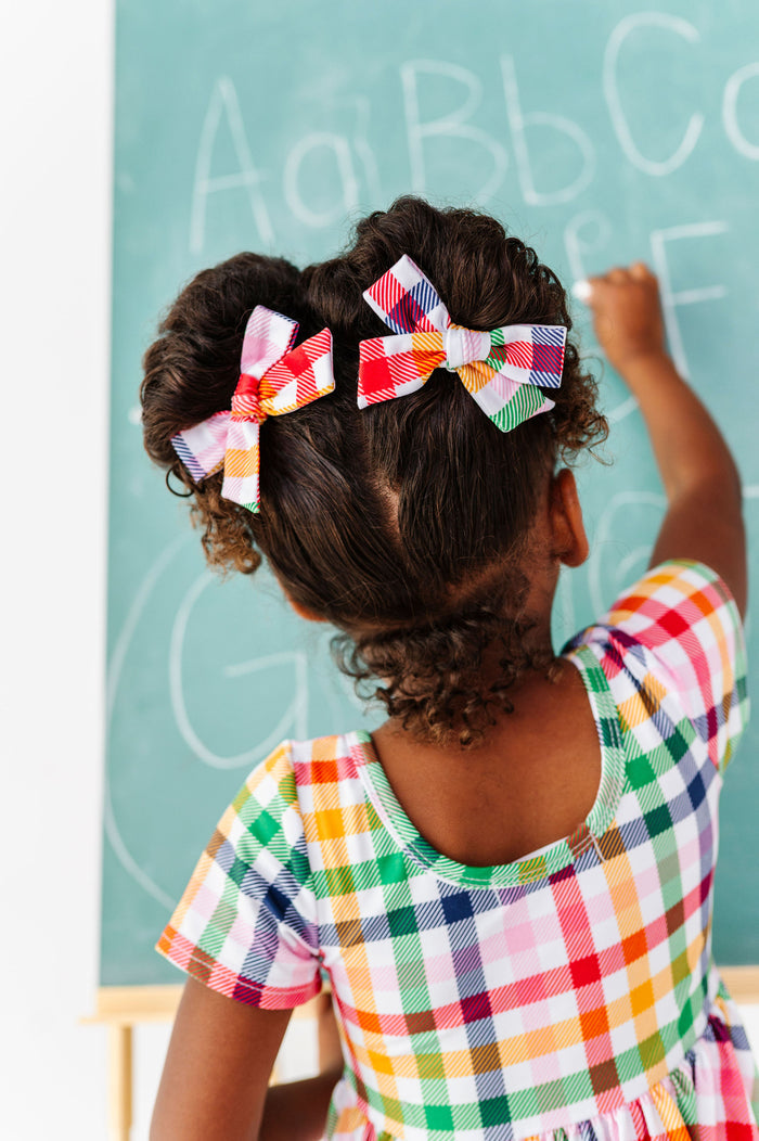 Girl wearing primary colors gingham hair bows in pigtails for back to school