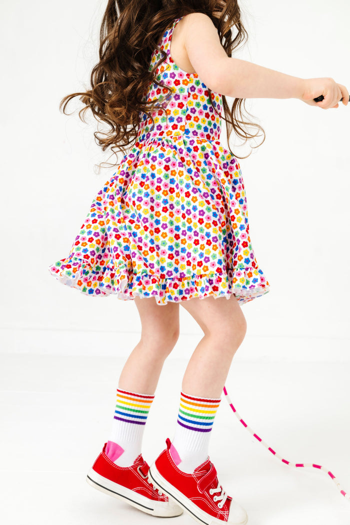little girl jumping rope in rainbow floral sleeveless summer twirl dress paired with rainbow striped crew socks and red sneakers