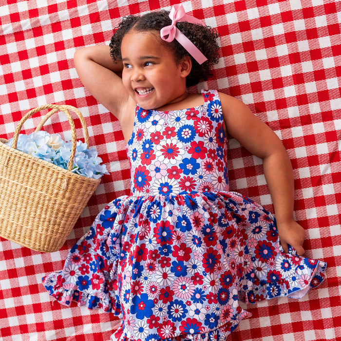 Child in a floral dress standing on a red and white checkered background