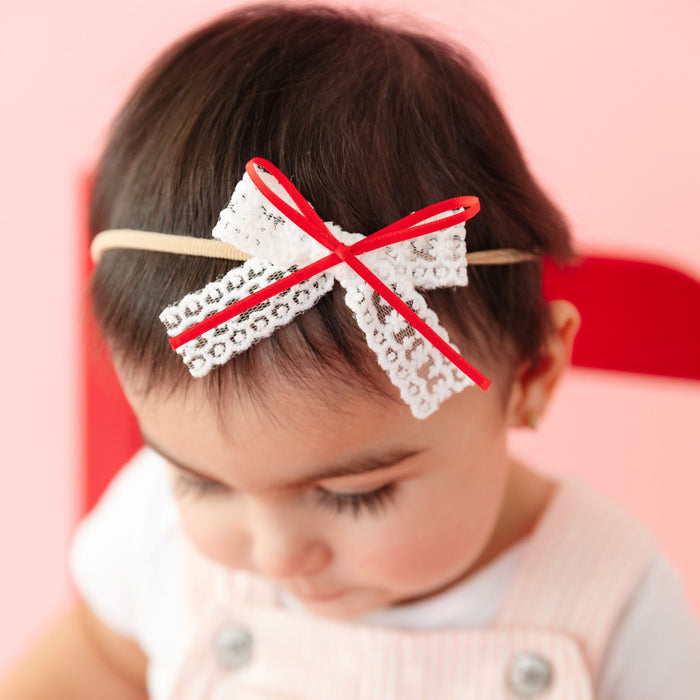 baby in white lace Valentine's Day bow with red ribbon on stretchy nylon headband