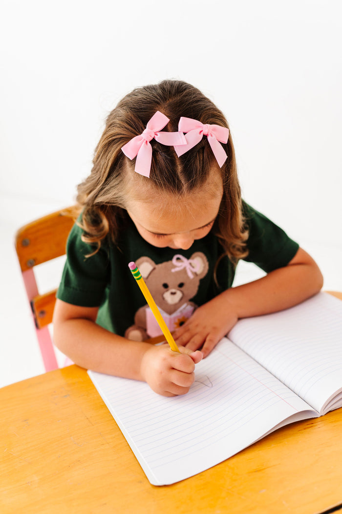 girl wearing pink satin pigtail hair bows with teddy bear sweater