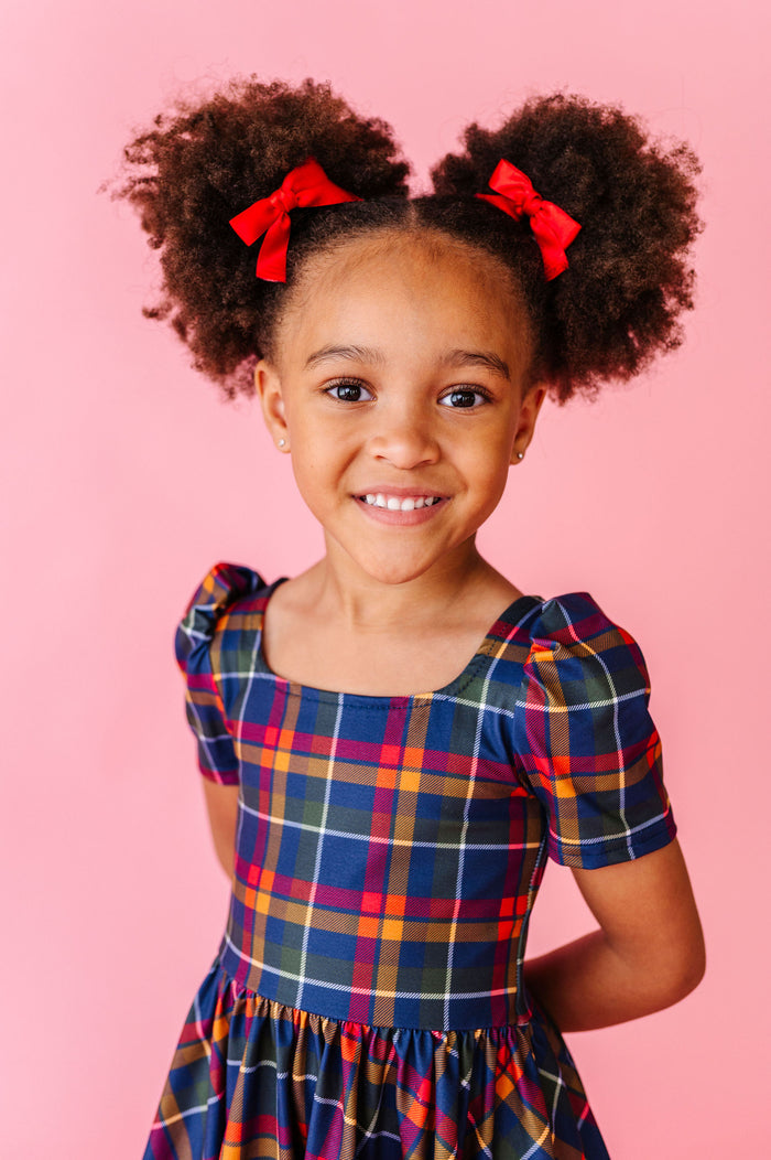 girl wearing red pigtail hair bows with plaid back to school dress
