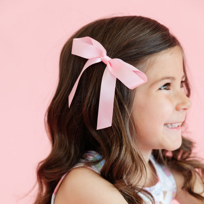 little girl with pastel pink satin ribbon bow on clip and matching sleeveless ice cream print dress for summer
