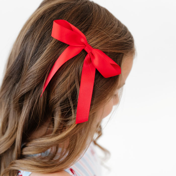 little girl wearing red satin bow on clip to match 4th of July bow print twirl dress