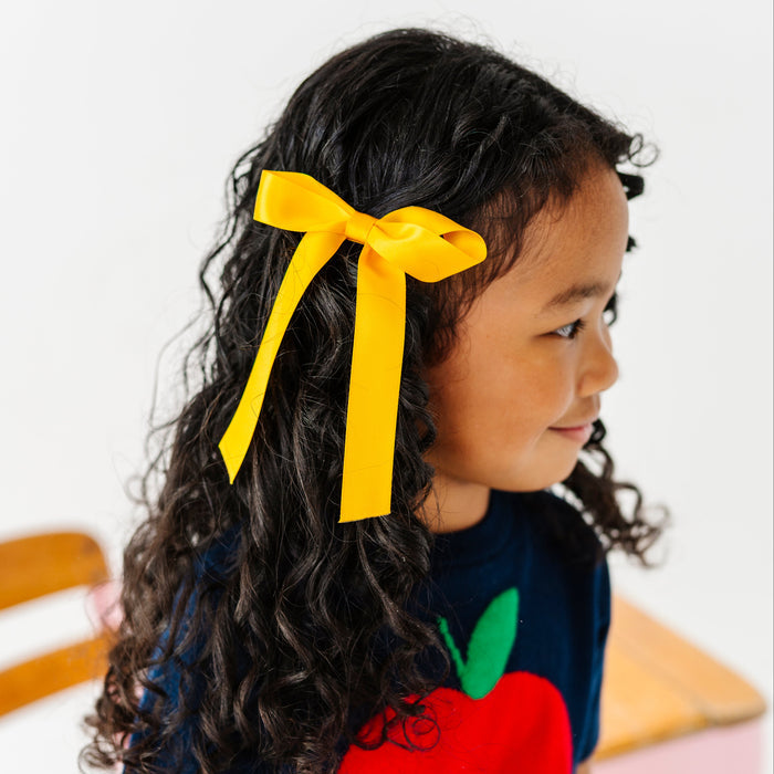 little girl in marigold yellow satin hair bow paired with navy blue apple sweater for school