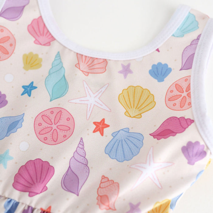 closeup of colorful seashell print on sandy cream background of twirl dress bodice