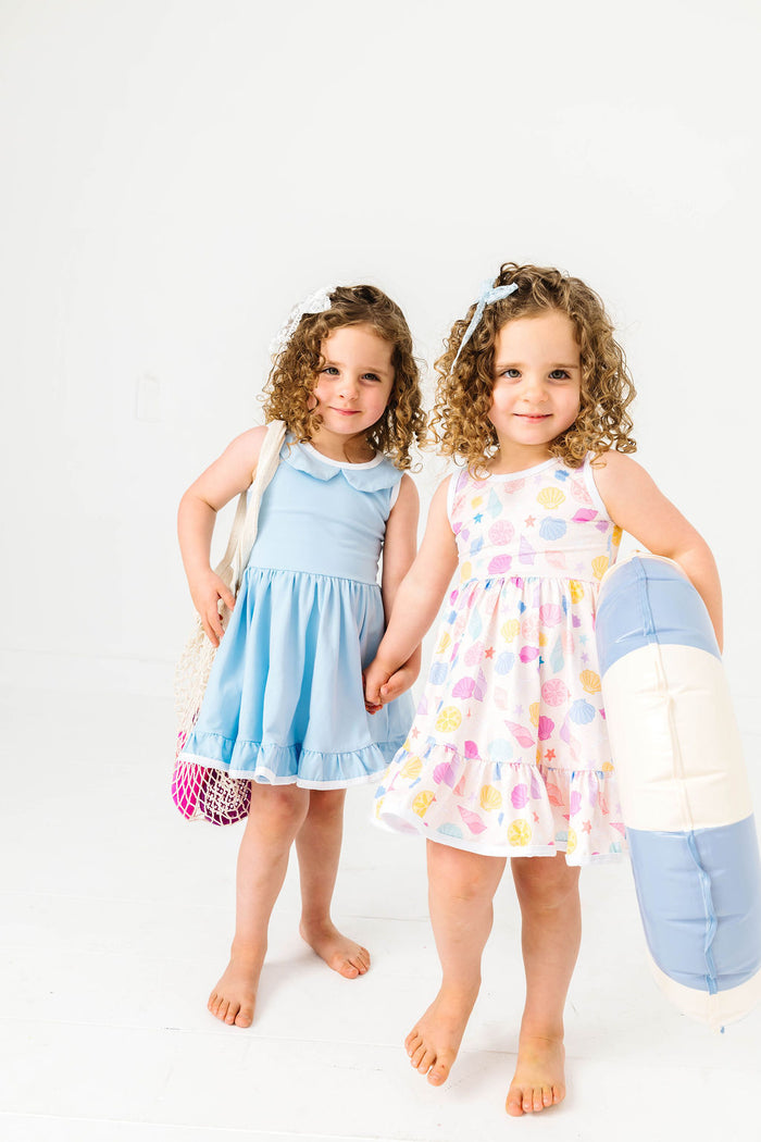 sisters in coordinating beachy seashell dress and matching light blue solid twirl dress for summer