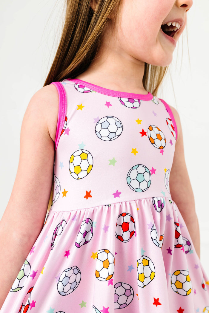 closeup of little girl in pink sleeveless twirl dress with colorful soccer ball and star print