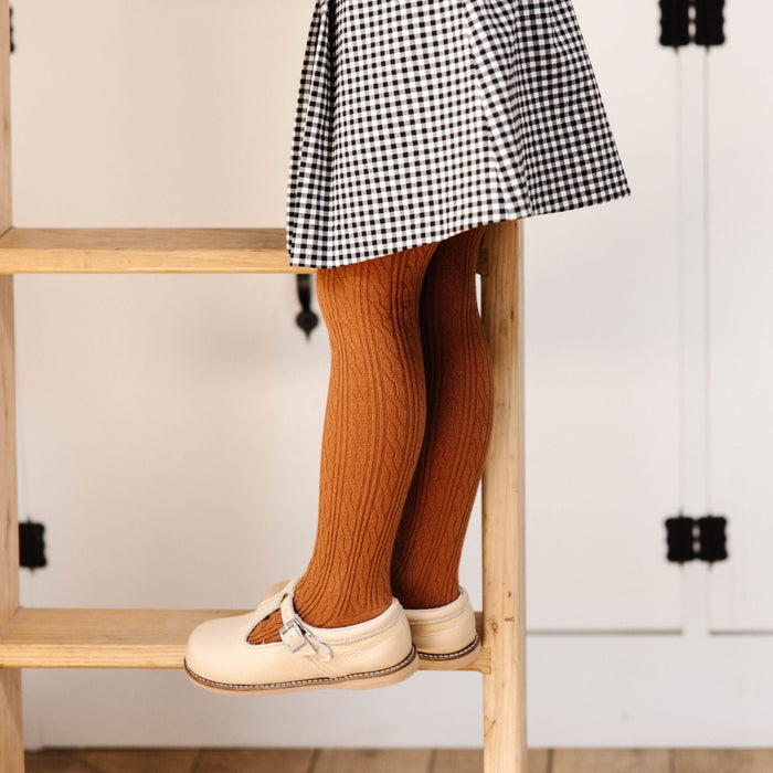 little girl standing on ladder in sugar almond cable knit tights