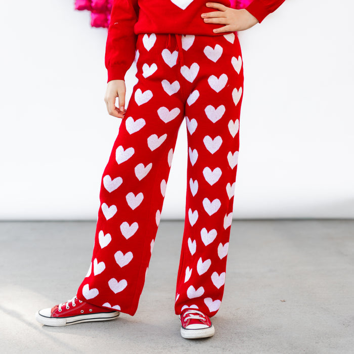 girl in bright red cotton knit sweater pants with white heart design and red sneakers