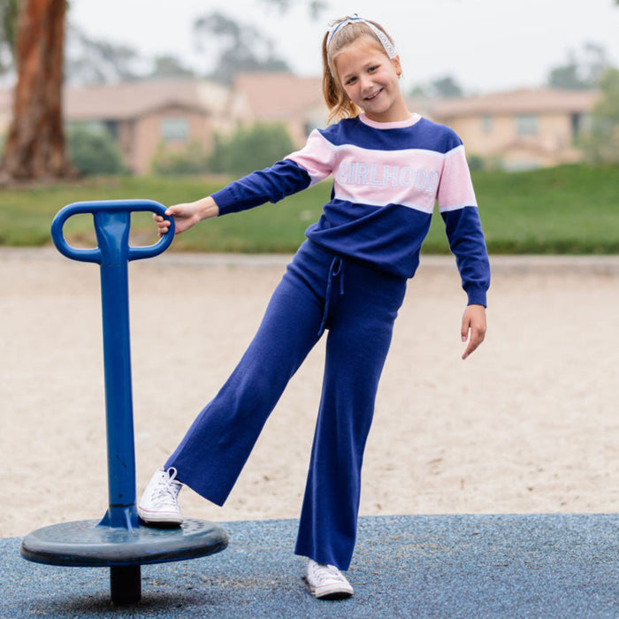 girl on the playground in navy and pink Girlhood sweater with matching navy sweater pants