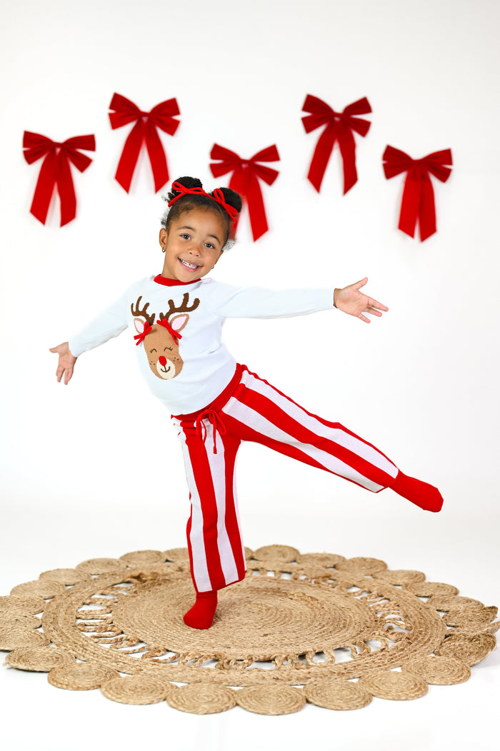 little girl in white pullover sweater with Rudolph design wearing 3D red pigtail bows paired with red and white striped sweater pants and red yarn pigtail bows for Christmas