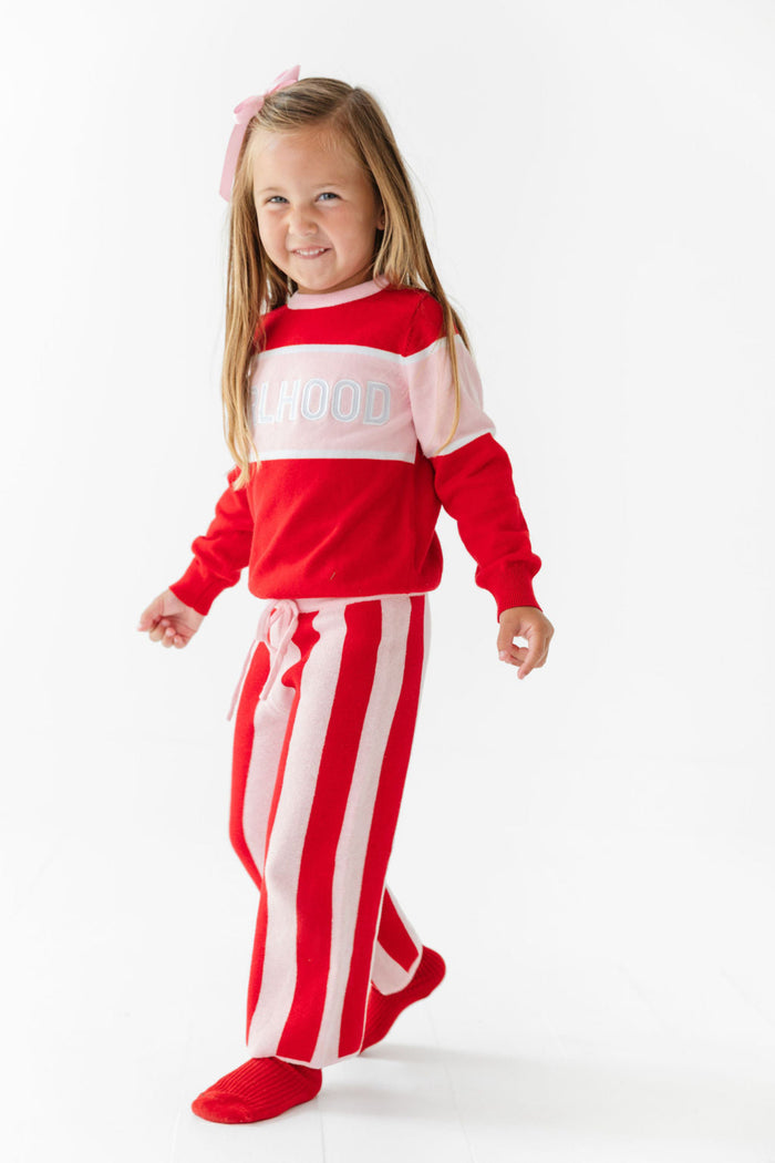 little girl in red and pink knit sweater with Girlhood design and matching red and pink sweater pants