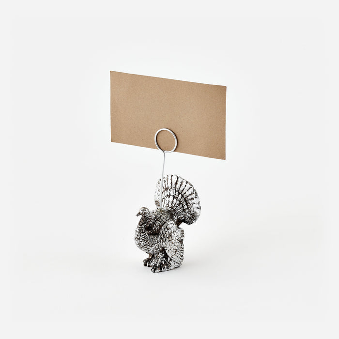 Metallic turkey-shaped card holder with a brown card on a white background