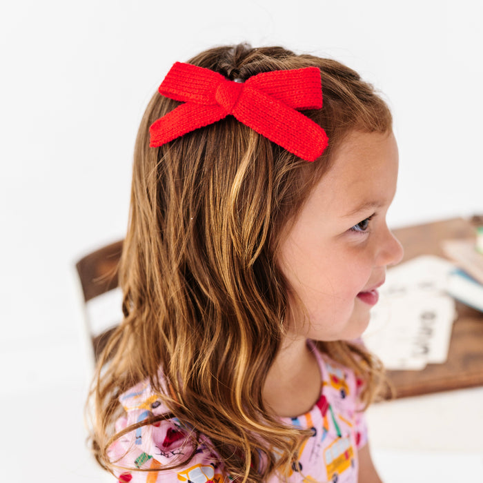 little girl in pink first day of school twirl dress paired with bright red yarn knit hair bow on clip